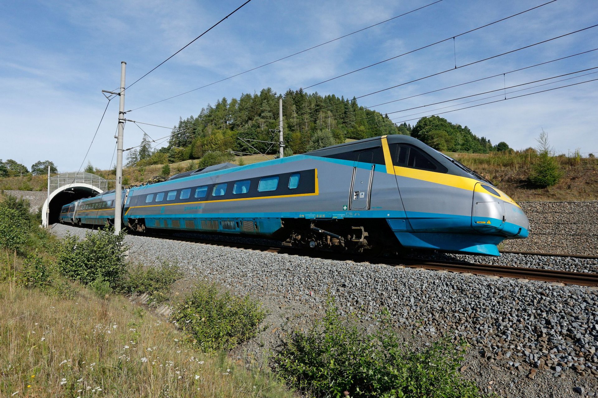 Jednotka Pendolino Českých drah projíždí po elektrifikované železniční trati u tunelu