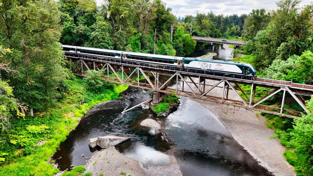 Souprava Amtrak Airo od Siemens Mobility projíždí po železničním mostě v zelené krajině na trase Amtrak Cascades