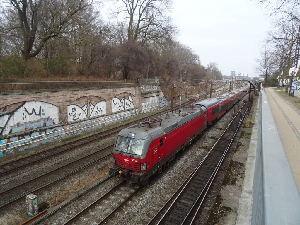 Dálková souprava Talgo 230 dopravce DSB vedená elektrickou lokomotivou Siemens Vectron EB 3217 na železniční trati v dánské Kodani