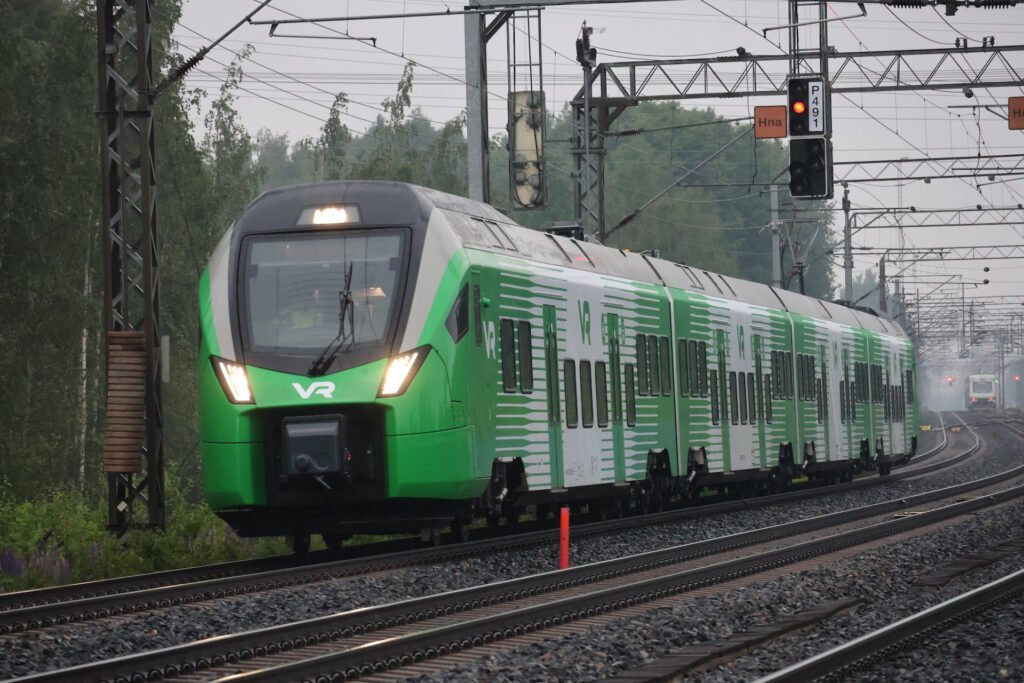 Zelenobílá elektrická jednotka Stadler FLIRT řady Sm7 během zkušební jízdy na elektrifikované železniční trati ve Finsku